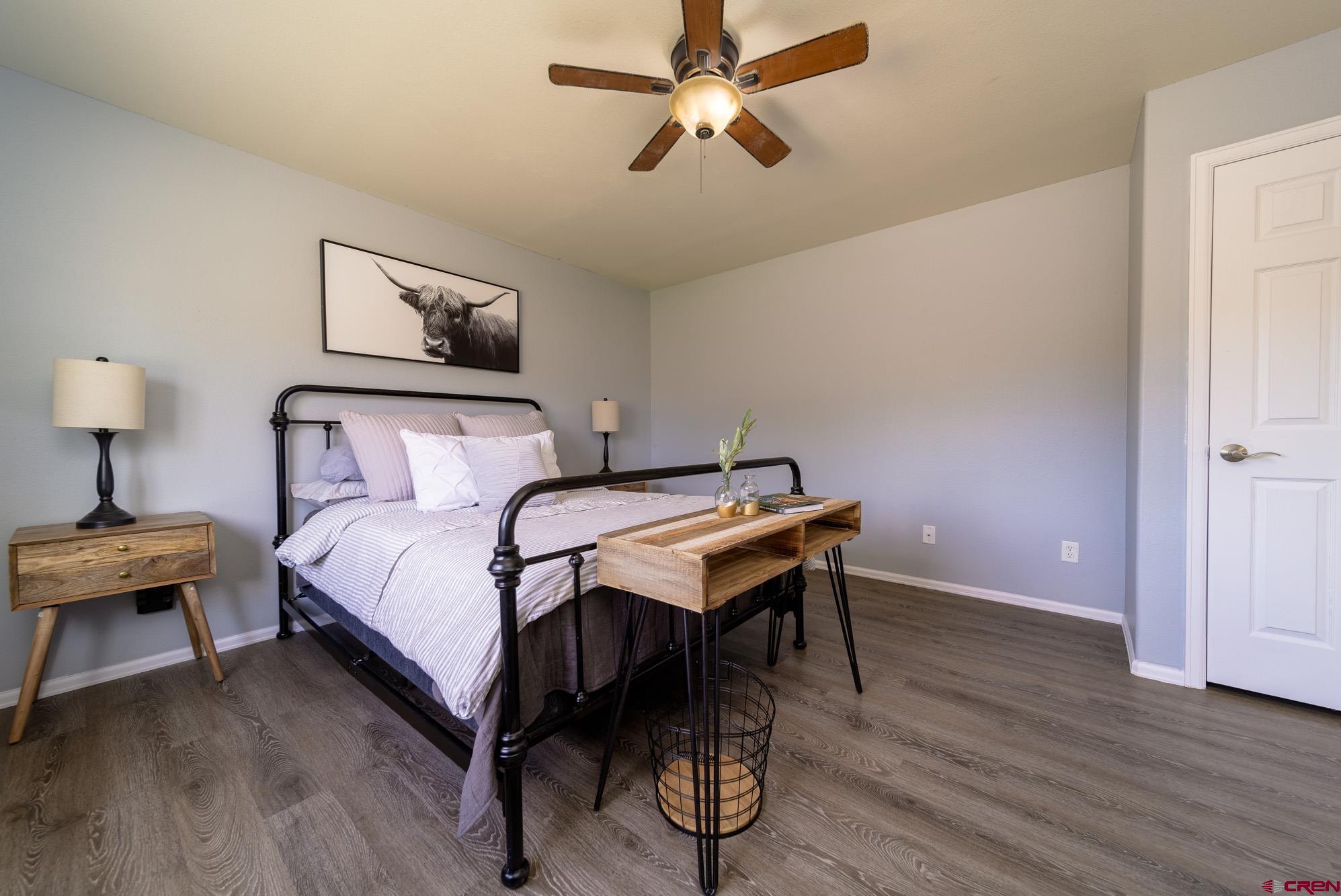 1531 Haystack Road Montrose, CO 81401 - Photo 14 of 34 a bedroom with a bed and a lamp on table with wooden floor