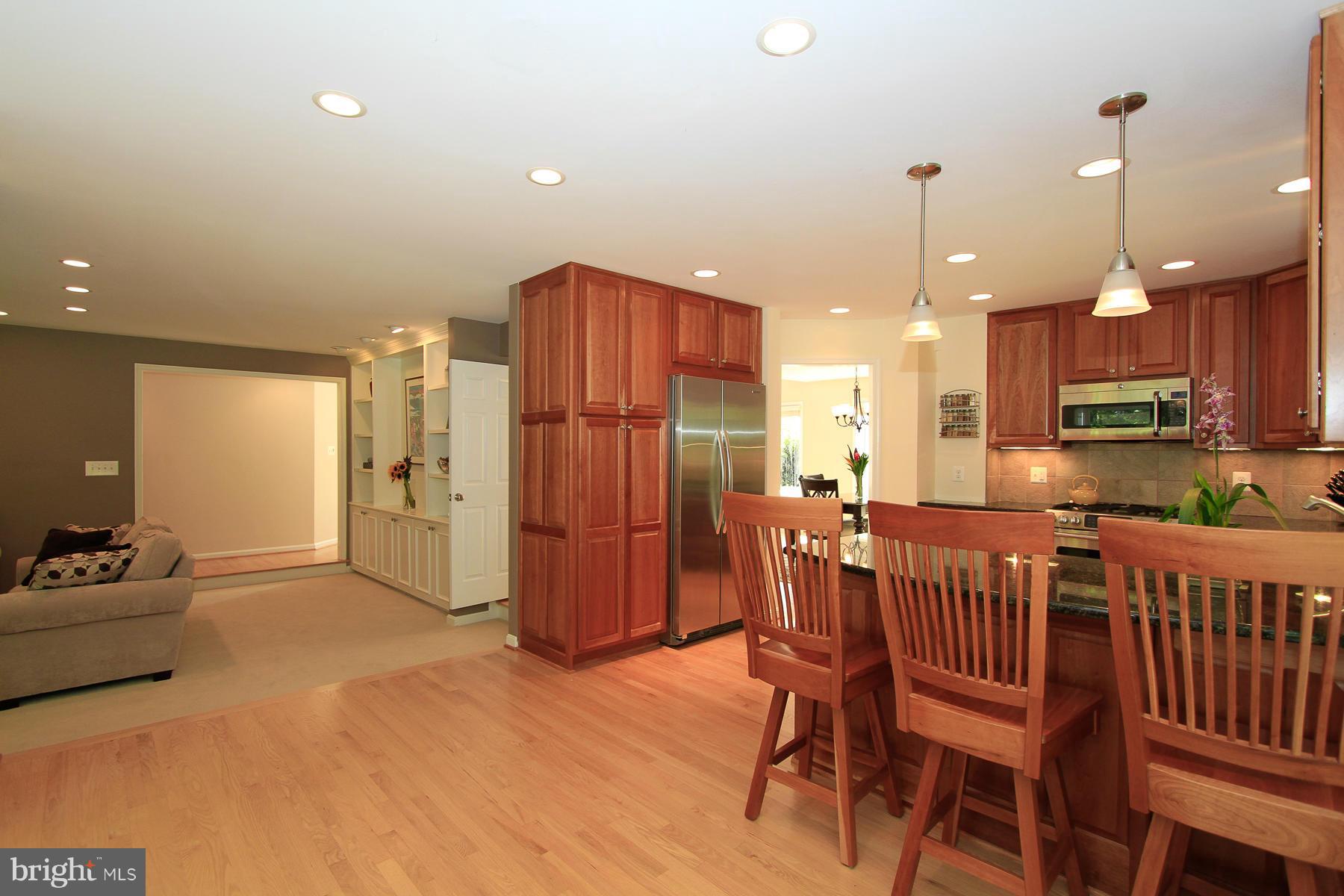 1304 Pavilion Club Way Reston, VA 20194 - Photo 10 of 30 a kitchen with stainless steel appliances kitchen island granite countertop a refrigerator a stove a kitchen island and chairs with wooden floor