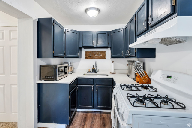 358 400 South Provo, UT 84601 - Photo 20 of 34 Kitchen with white gas range, light countertops, stainless steel microwave, dark wood-type flooring, and a textured ceiling.