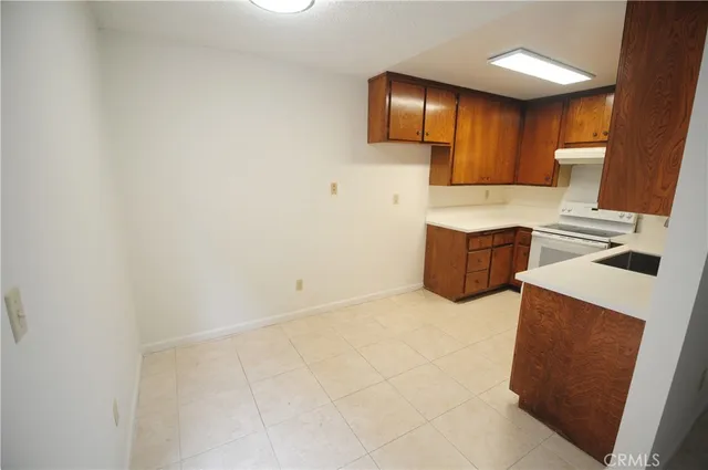 a kitchen with granite countertop a sink a stove top oven and cabinetry