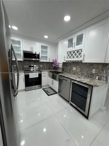 a kitchen with stainless steel appliances kitchen island granite countertop a stove top oven a sink a counter top space and cabinets