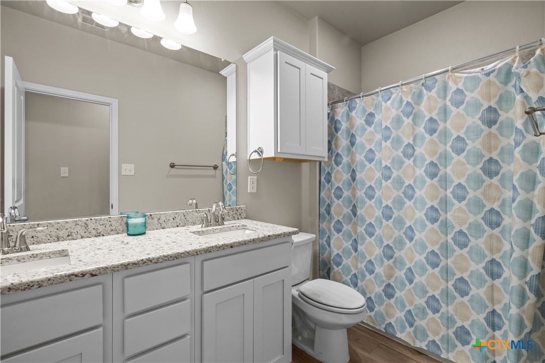 620 Ripplewood Drive Temple, TX 76502 - Photo 19 of 29 a bathroom with a granite countertop sink a toilet and a mirror