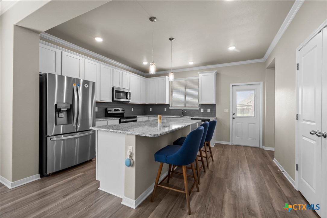 620 Ripplewood Drive Temple, TX 76502 - Photo 7 of 29 a kitchen with stainless steel appliances granite countertop a refrigerator a sink dishwasher a stove and white countertops with wooden floor