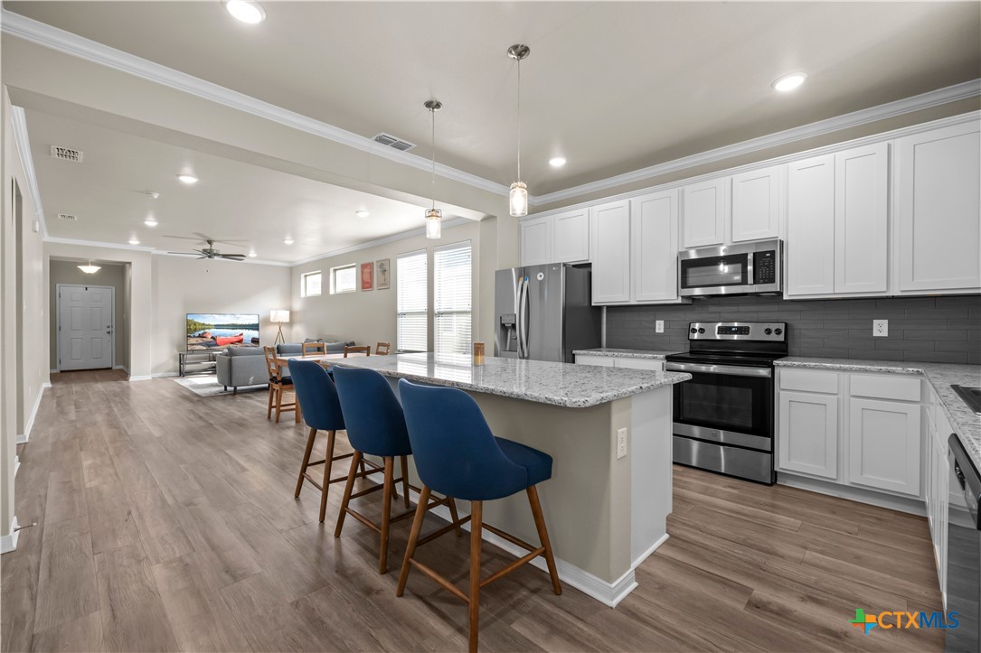 620 Ripplewood Drive Temple, TX 76502 - Photo 10 of 29 a kitchen with stainless steel appliances granite countertop a stove a sink a microwave a refrigerator and white cabinets with wooden floor