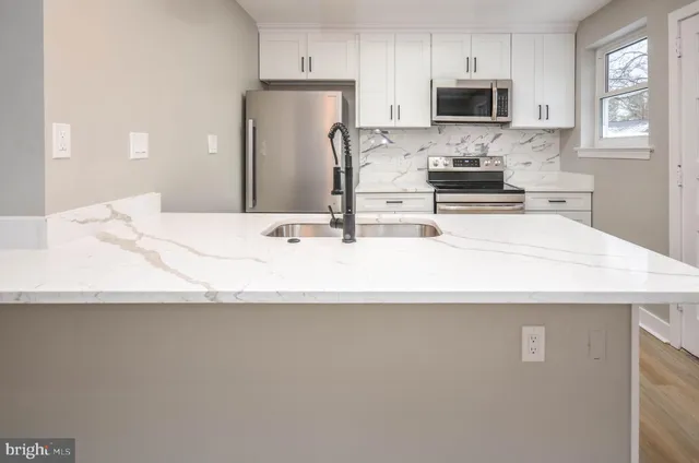 a kitchen with stainless steel appliances a sink a stove top oven a counter space and cabinets