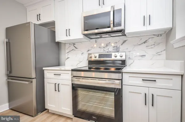 a kitchen with stainless steel appliances white cabinets and a refrigerator