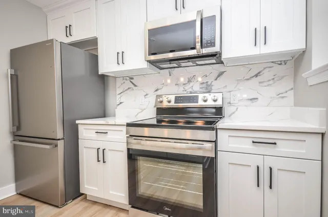a kitchen with stainless steel appliances white cabinets and a refrigerator