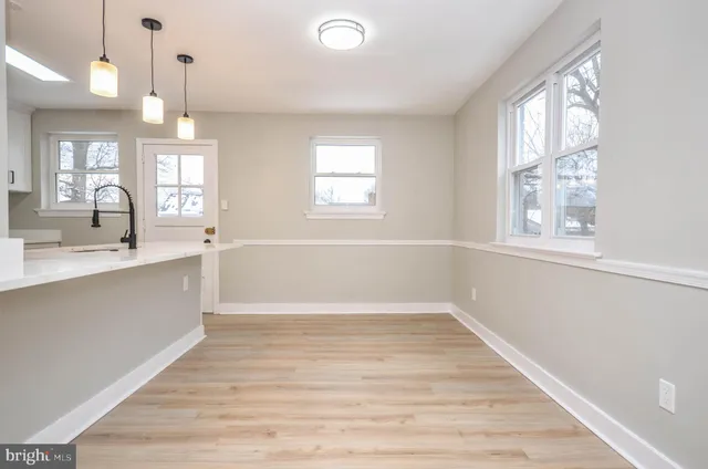 a view of an empty room with window and wooden floor