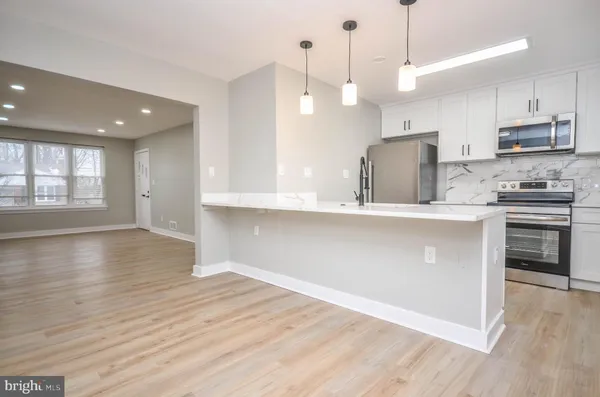 a kitchen with stainless steel appliances granite countertop a sink a stove a refrigerator and a window with wooden floors