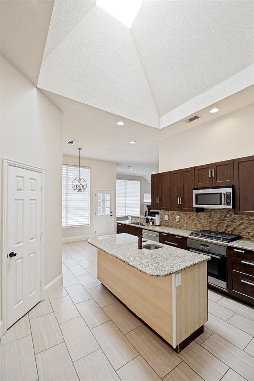 2100 Los Rios Boulevard Plano, TX 75074 - Photo 12 of 25 Kitchen featuring a central island with a light wood-finish base and granite countertop