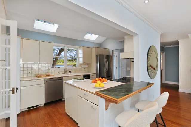 a kitchen with stainless steel appliances granite countertop a stove refrigerator sink and a dining table