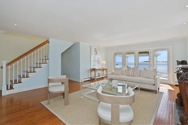 a living room with couches and a dining table with wooden floor