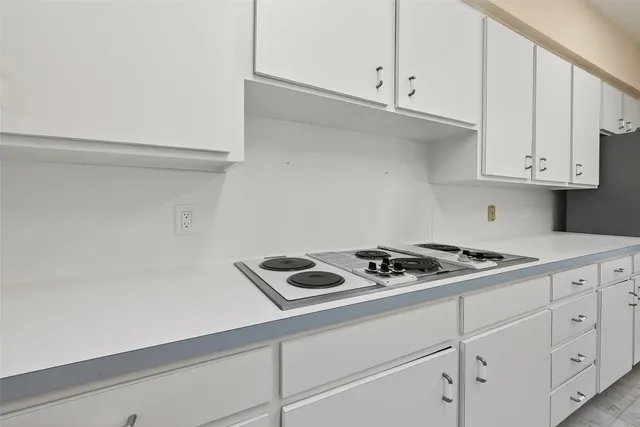 a kitchen with white cabinets stove and sink
