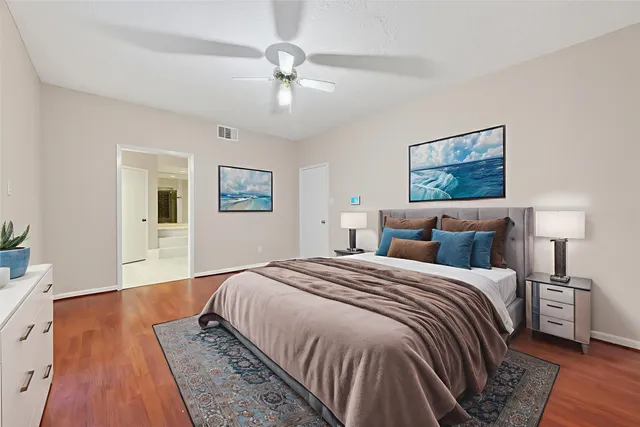 a view of an empty room with wooden floor and a ceiling fan