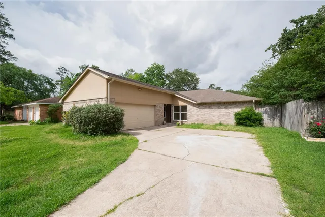 a view of a yard in front of a house with plants and large tree