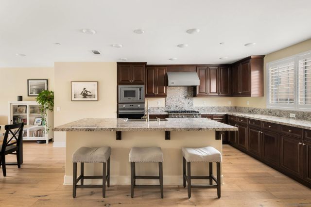 a kitchen with stainless steel appliances granite countertop a stove a sink dishwasher a stove and white cabinets with wooden floor