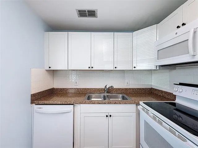 a kitchen with stainless steel appliances granite countertop white cabinets sink and granite counter tops