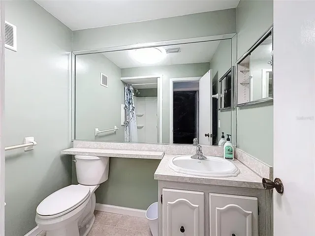 a bathroom with a granite countertop toilet sink and mirror