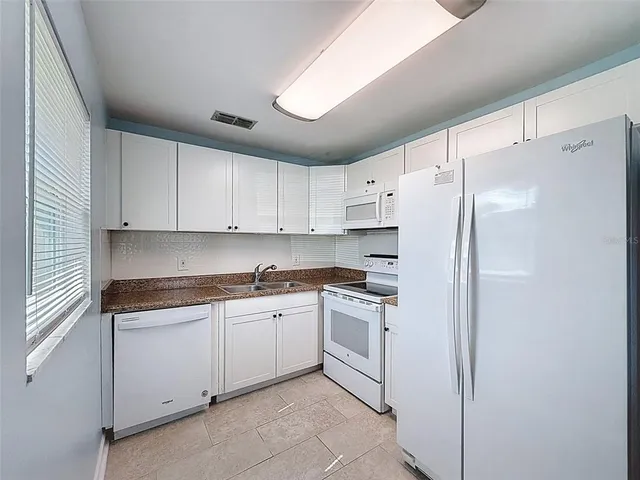 a kitchen with white cabinets and white appliances