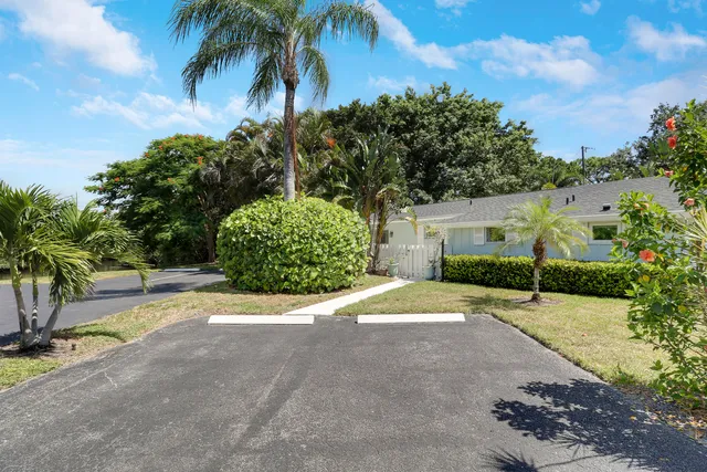 a pathway of a house with a yard and palm trees
