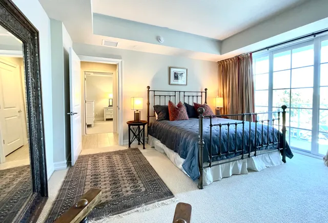 a bedroom with a bed lamp and a large window with outer view