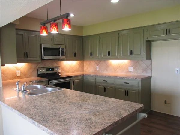 a kitchen with kitchen island granite countertop stainless steel appliances and a counter top space