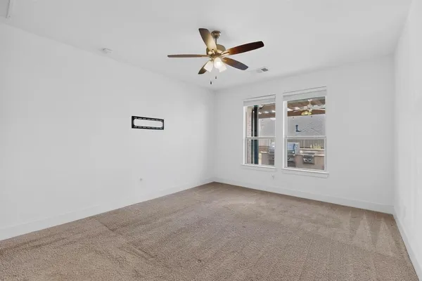 an empty room with ceiling fan and windows
