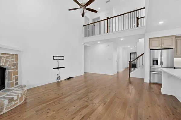 a view of empty room with wooden floor and a kitchen