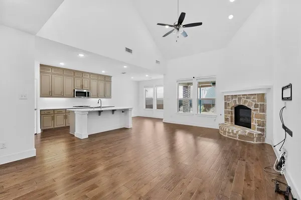 a living room with stainless steel appliances kitchen island a fireplace and wooden floors