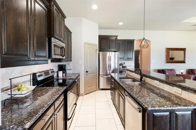 a kitchen with stainless steel appliances granite countertop a kitchen island a stove and a sink