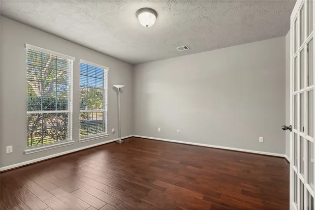 a view of an empty room with wooden floor and a window