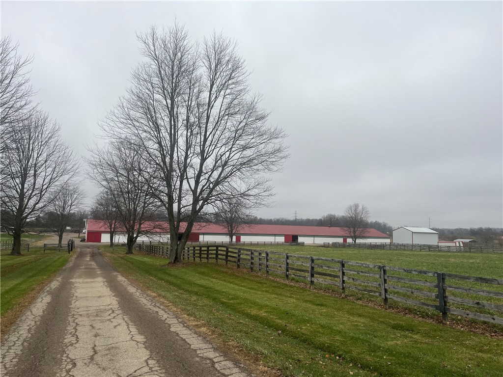 This expansive estate features a long driveway leading to multiple outbuildings amidst lush green pastures.
