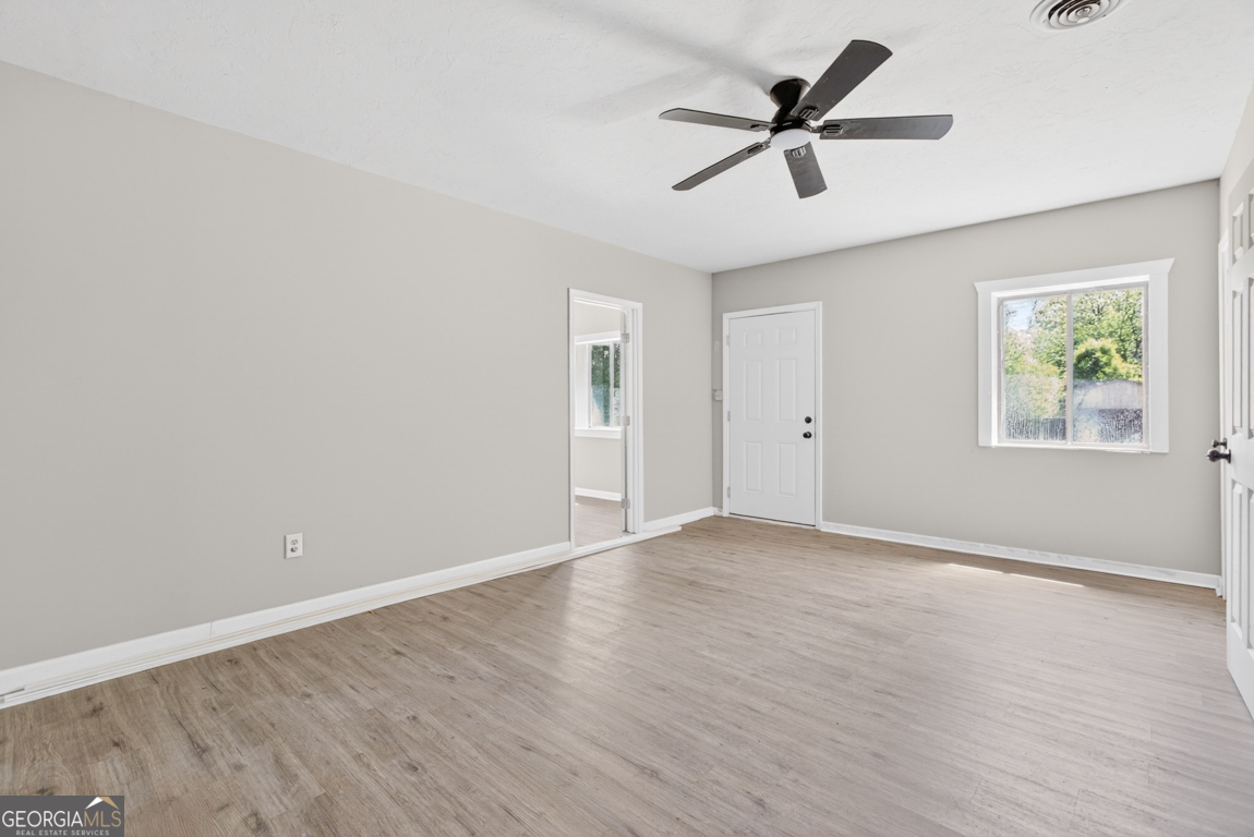 481 Main Street Clermont, GA 30527 - Photo 33 of 43 an empty room with wooden floor ceiling fan and windows