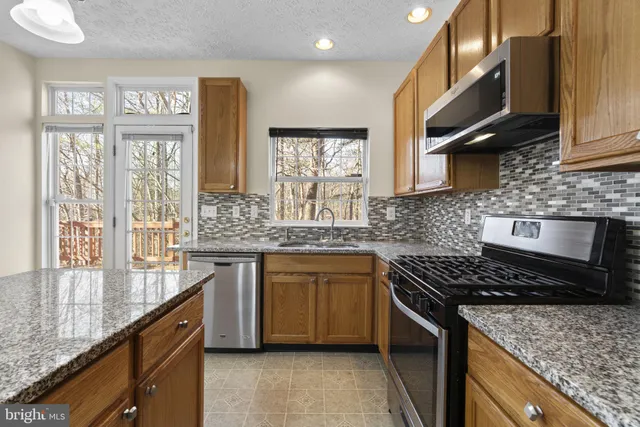 a kitchen with stainless steel appliances granite countertop a sink stove and cabinets