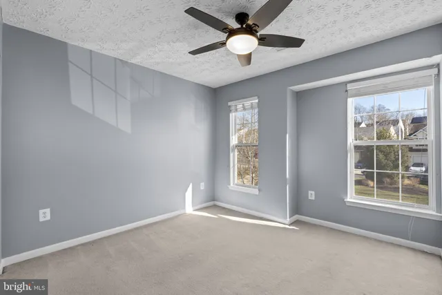 a view of an empty room and chandelier fan