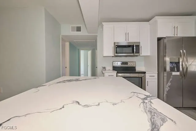 a kitchen with granite countertop a refrigerator stove and microwave