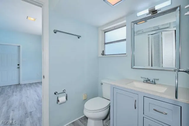 a bathroom with a toilet sink vanity and mirror