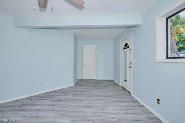 a view of an empty room with wooden floor and a window