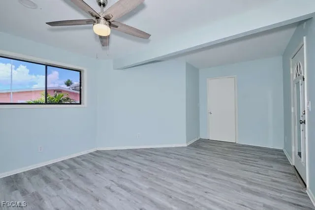 an empty room with wooden floor closet and ceiling fan