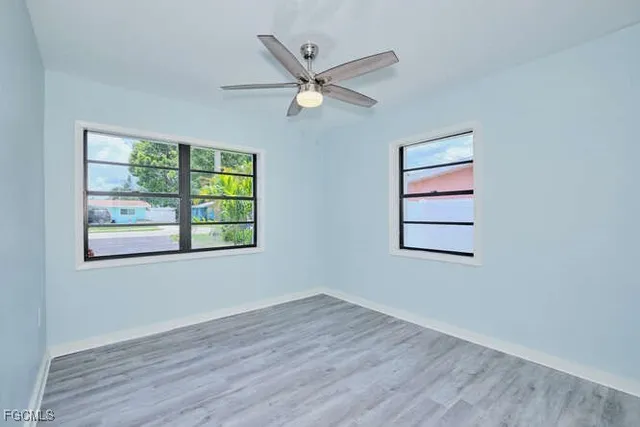 a view of an empty room with wooden floor and a ceiling fan