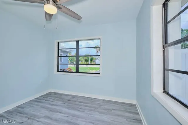a view of an empty room with a window and wooden floor