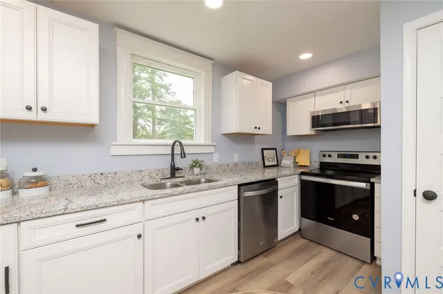 a kitchen with stainless steel appliances granite countertop white cabinets granite counter tops and a window