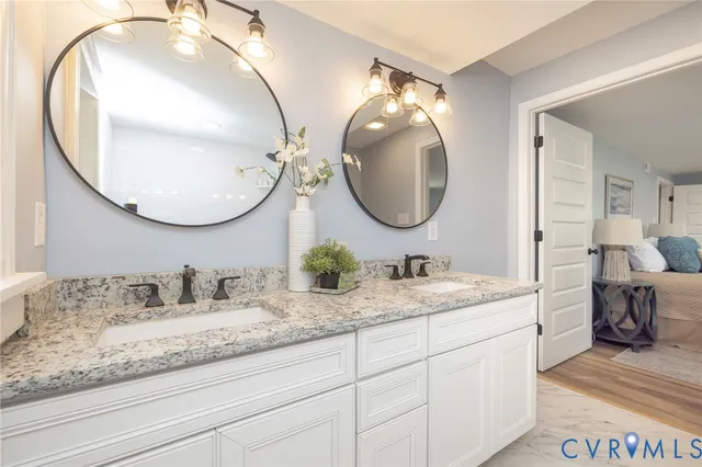 a en suite bathroom with a granite countertop double vanity and a mirror