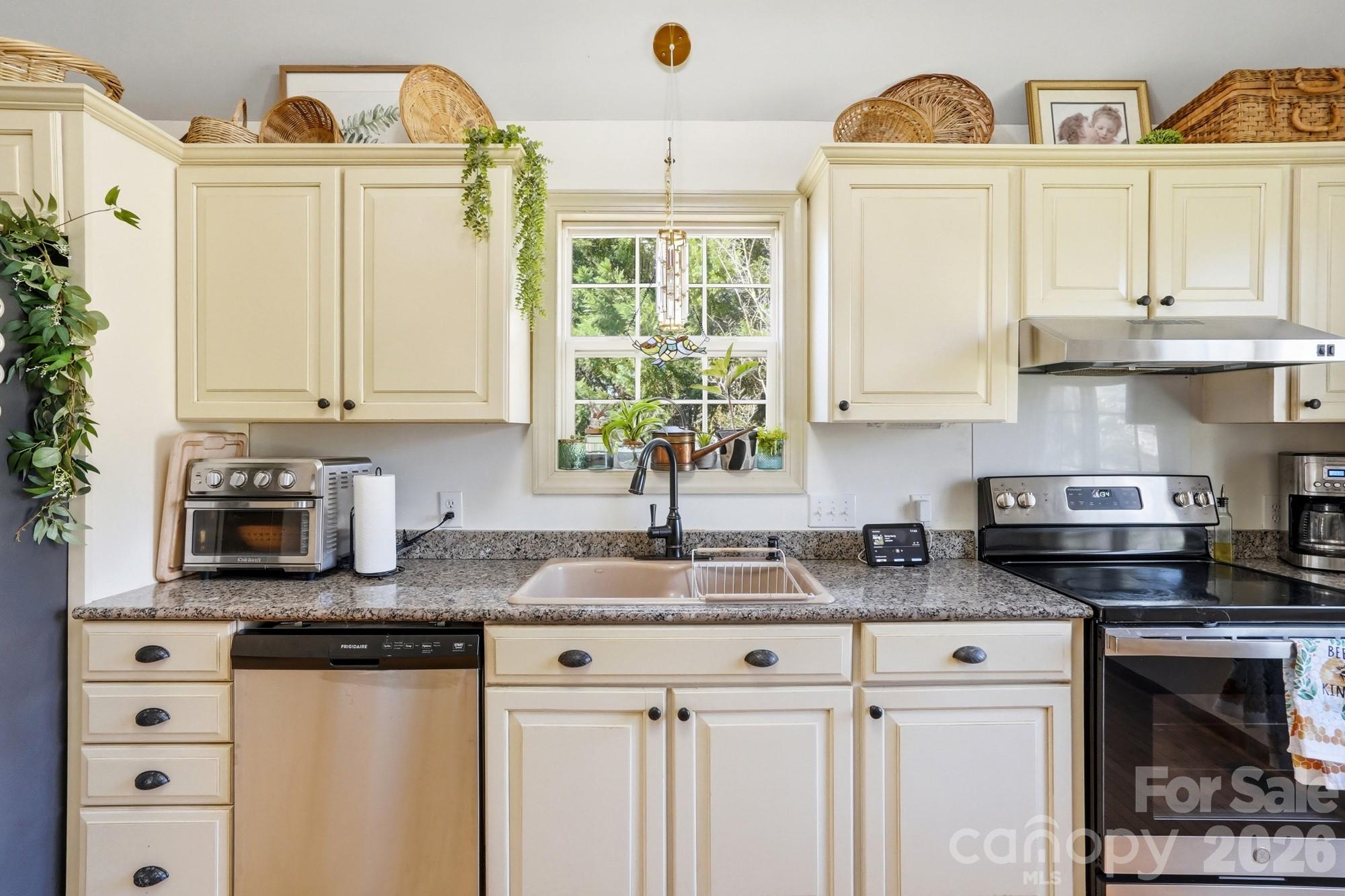 6046 Windjammer Drive Tega Cay, SC 29708 - Photo 18 of 46 a kitchen with stainless steel appliances granite countertop a sink a stove and a window