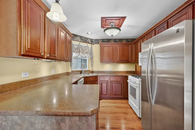 a kitchen with stainless steel appliances granite countertop a refrigerator a sink and a stove
