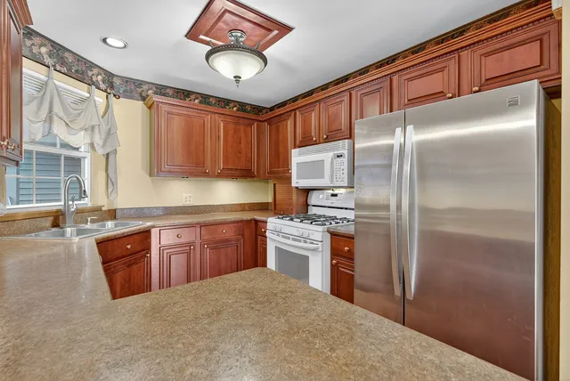 a kitchen with stainless steel appliances granite countertop a refrigerator a stove and a sink with cabinets