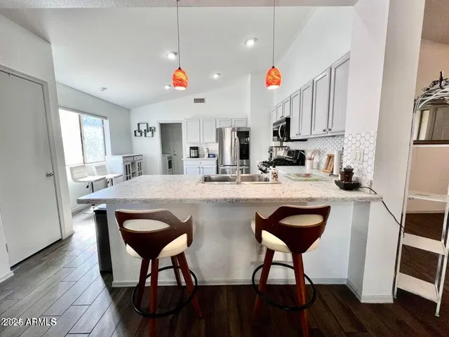 a kitchen with stainless steel appliances granite countertop a dining table chairs sink and cabinets