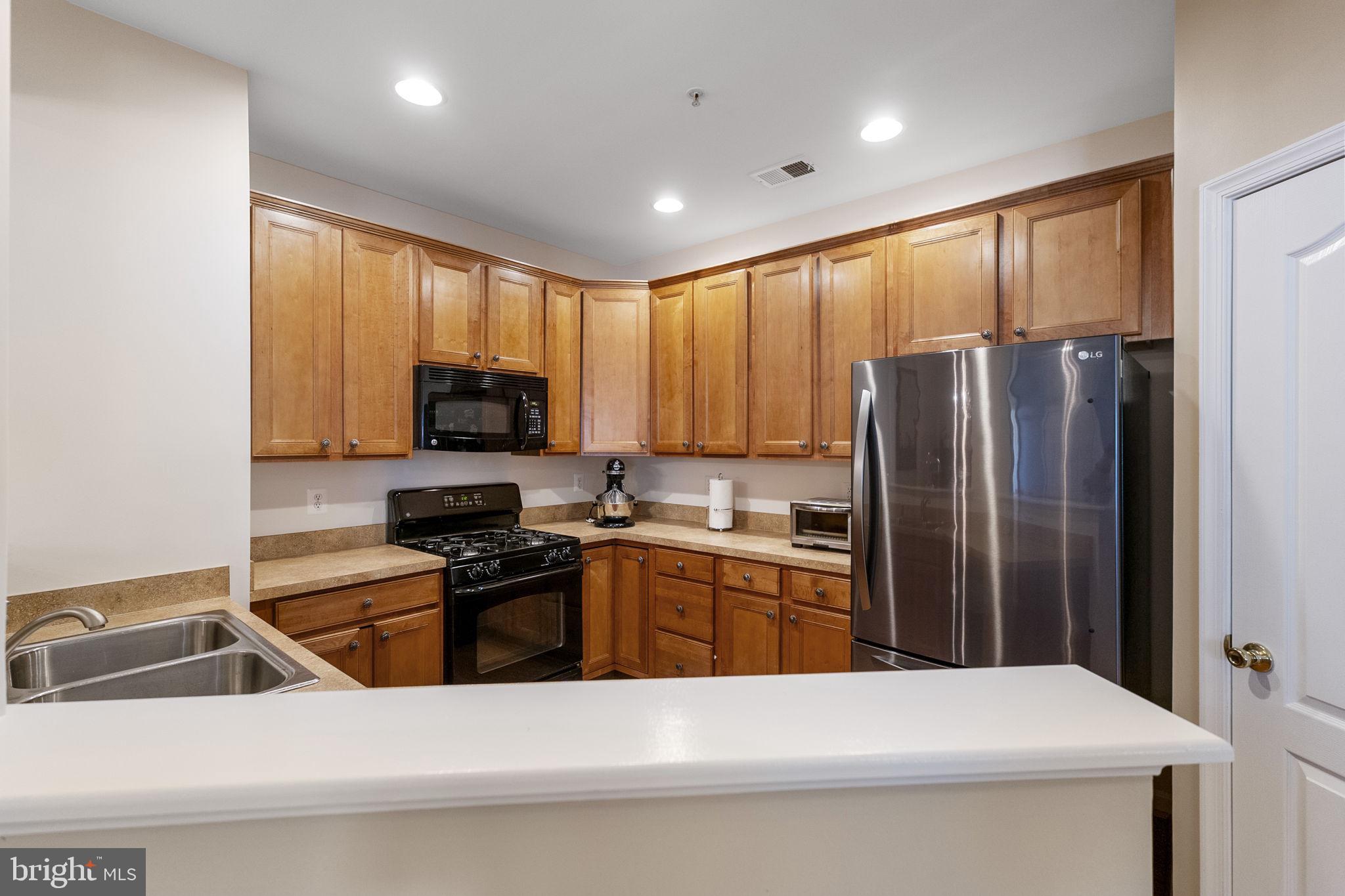 127 Mountain Creek Circle Frederick, MD 21702 - Photo 3 of 26 a kitchen with stainless steel appliances a refrigerator a stove a sink a stove a dining table and chairs with wooden floor