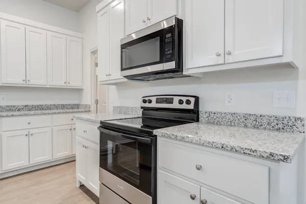 a kitchen with granite countertop white cabinets and a stove a oven with white countertops