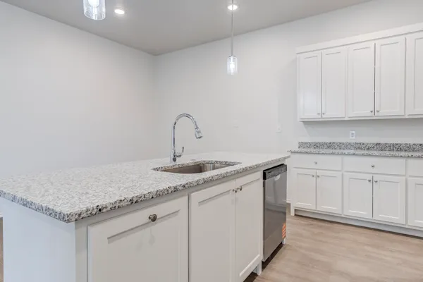 a kitchen with granite countertop white cabinets and a sink